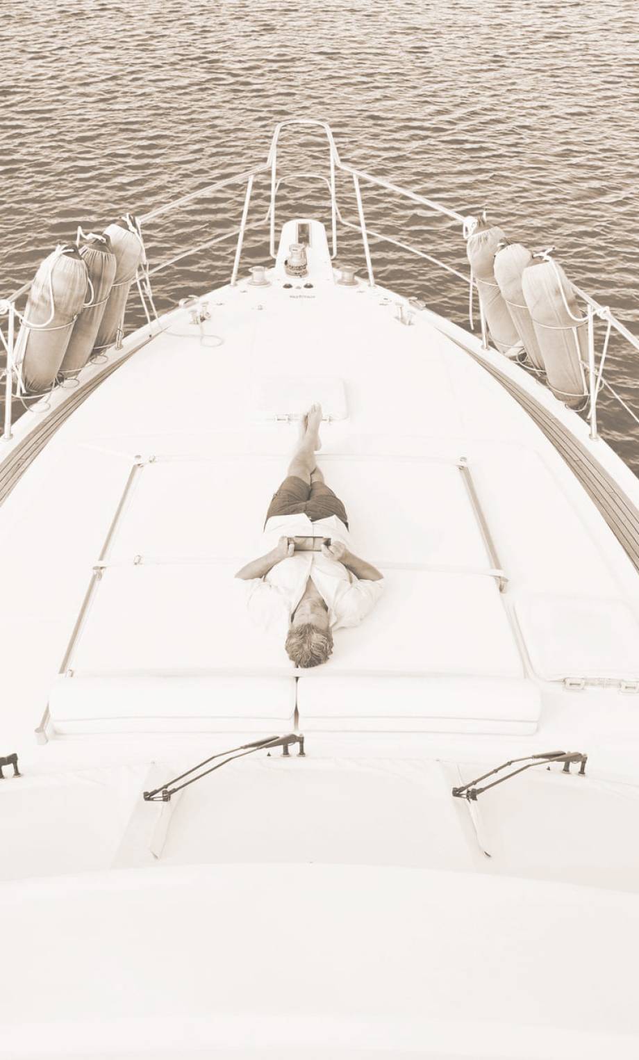 smiling-man-lying-on-deck-of-his-motor-yacht-using-2023-11-27-05-02-25-utc-min (1)-min